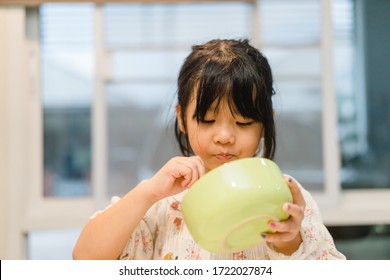 Hungry face and enjoy eating enjoy food concept.Little asian girl enjoy eating with noodle with spoon on a bowl in breakfast.Stay at home.Eat, Food, Lockdown from covid-19, Oral health dental care.