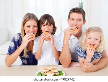 Hungry Family Eating Burgers In The Living Room At Home