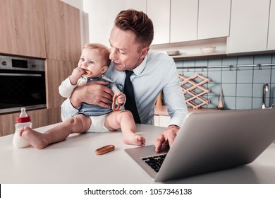 I am hungry. Funny girl sitting on the table and eating bagel while looking aside - Powered by Shutterstock