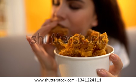 Hungry girl eating fried chicken wings, addiction to unhealthy but tasty food