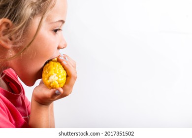 Hungry Girl Eating Sweet Corn On A White Background With Copy Space.