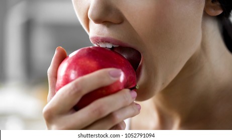 Hungry girl with great appetite biting big juicy apple, healthy snack at work