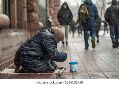 Hungry Homeless Beggar Woman Beg For Money On The Urban Street In The City From People Walking By