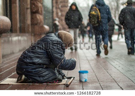 Hungry homeless beggar woman beg for money on the urban street in the city from people walking by