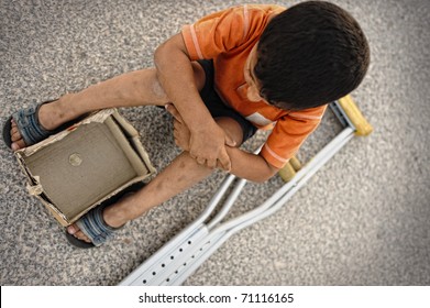 Hungry Kid Begging On The Street With A Crutches Beside