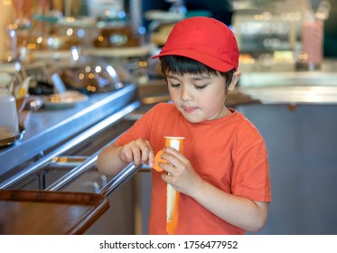 Hungry Kid Licking Lips Looking At Ice Lolly With Blurry Cafe Background, Happy Child Boy Standing In The Front Of Cake Shop Eating Ice Cream Lollipop. Frozen Ice Pop Treat In The Summer For Kids