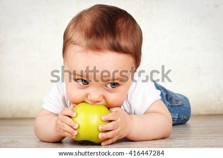 Hungry little baby boy eating apple