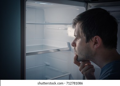 Hungry Man Is Looking For Food To Eat In Empty Fridge At Night.