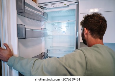 Hungry Man Is Looking For Food In Empty Fridge At Night.