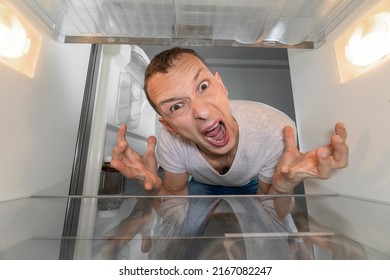 Hungry Person Is Looking For Food In Refrigerator And Is In Shock. An Empty Refrigerator. Guy Is Upset, Screams And Breaks Down. Crisis And Lack Money. Family Starving. Depression Of Man Without Money