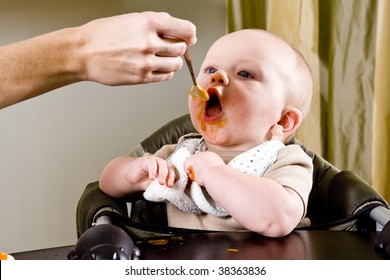 Hungry Six Month Old Baby Eating Solid Food From A Spoon