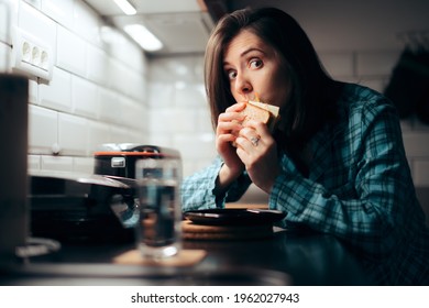 Hungry Woman Eating A Sandwich At Night In The Kitchen. Young Person Stress Eating During Nighttime Having A Late Snack 
