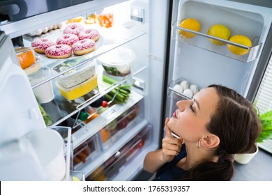 Hungry Woman Looking For Food In Kitchen At Home