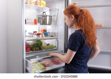 Hungry Woman Looking For Food In Kitchen At Home