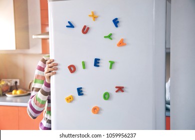 Hungry Woman Looking In Open Fridge With Diet Letters On Door