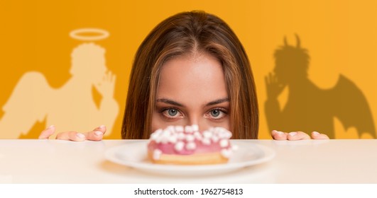 Hungry woman looking at yummy donut from under table, angel and devil tempting her, orange studio background, collage. Panorama. Concept of choice between healthy diet and unhealthy foods