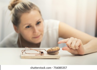 hungry woman trying to steal cookie from mouse trap. weight loss diet plan concept
