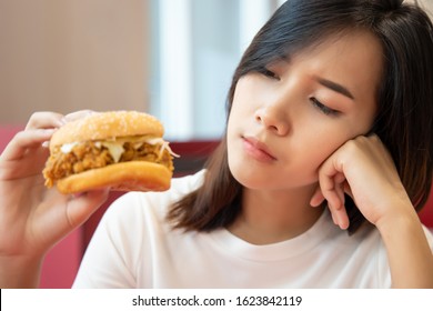 Hungry Worried Woman On Diet Looking And Hesitating To Eat Fried Chicken Burger Sandwich; Concept Of Unhealthy Delicious Food, Unhealthy Eating Habit, Junk Food, Fast Food, Woman Having No Appetite