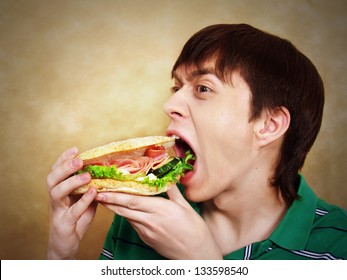 The hungry young man aggressively eats a hamburger. Fast food