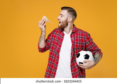 Hungry Young Man Football Fan In Red Shirt Cheer Up Support Favorite Sport Team With Soccer Ball Eating Italian Pizza Isolated On Yellow Background Studio Portrait. Tattoo Translation Life Is Fight