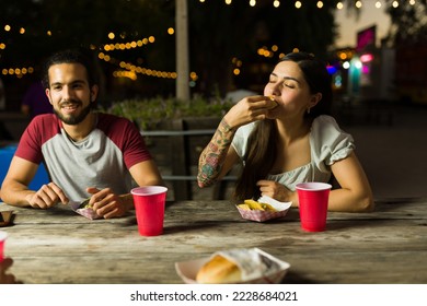 Hungry young woman and man eating delicious street tacos with friends at the food truck at night - Powered by Shutterstock