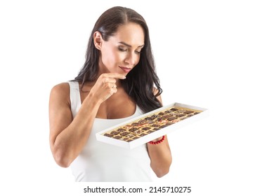 Hungy Brunette Is Making A Hard Decision With A Candy Box Full Of Tasty Chocolates. Isolated Background.