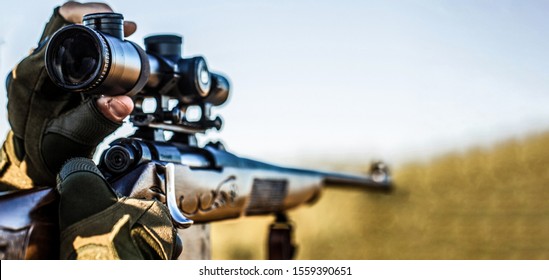 Hunt hunting rifle. Hunter man. Hunting period. Male with a gun. Close up. Hunter with hunting gun and hunting form to hunt. Hunter is aiming. Shooter sighting in the target.
