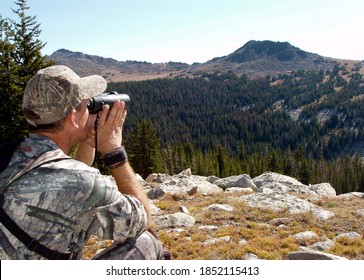 Hunter in camouflage using binoculars to search Montana hills for animals