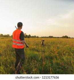 Hunter In The Fall Hunting Season With His Hunting Dog On Sunset. Square.