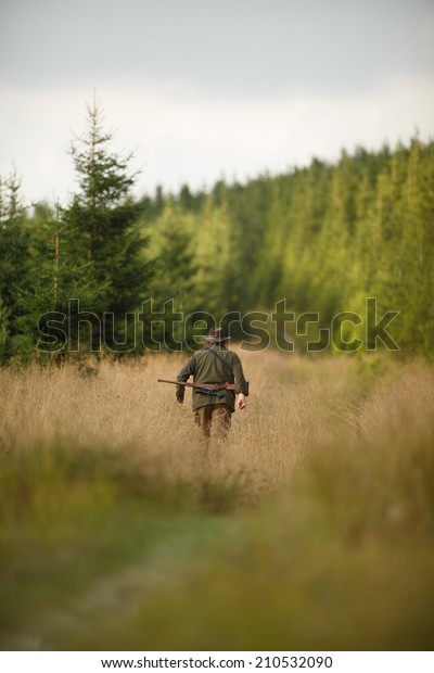 hunter with his rifle in spring forest, hunter\
holding a rifle and  waiting for prey, hunter shooting, gamekeeper\
on the walk