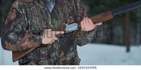 Cazador sosteniendo una escopeta de doble cañón listo para la acción.