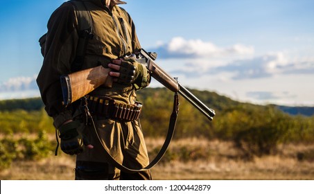 Hunter man. Hunting period, autumn season. Male with a gun. A hunter with a hunting gun and hunting form to hunt in an autumn forest. The man is on the hunt. Hunter with a backpack and a hunting gun. 