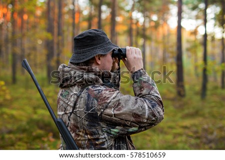 Hunter observing forest with binoculars