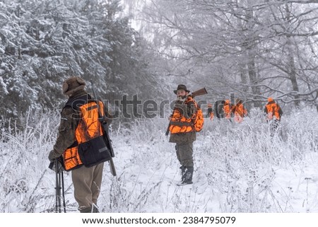 Hunters during winter hunting, walking in the forest 