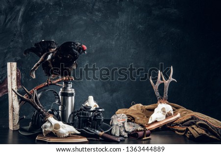 Hunters equipment and trophys on a table. Studio photo against dark wall background