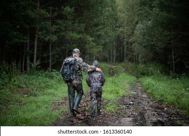 Hunters with hunting equipment going away through rural field towards forest at sunset during hunting season in countryside. - Powered by Shutterstock