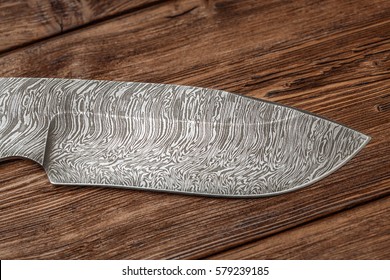 Hunting damascus steel knife handmade on wooden background.