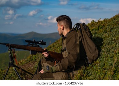 Hunting Gear - Hunting Supplies And Equipment. Man With Gun. Hunter On Big Game Or Small Game. Handsome Hunter Man Holding Gun And Walking In Forest