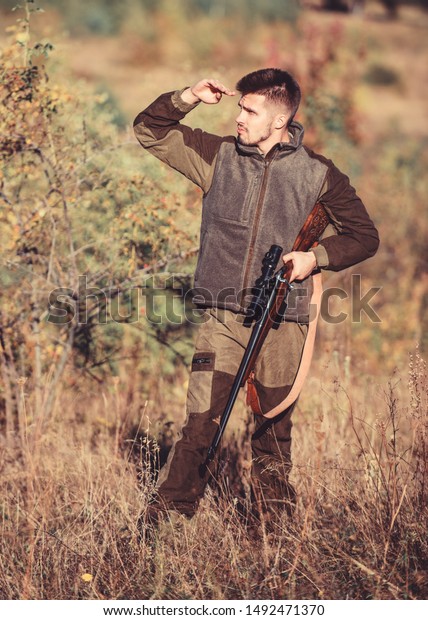 Hunting permit. Bearded serious hunter spend\
leisure hunting. Hunter hold rifle. Hunting is brutal masculine\
hobby. Hunting and trapping seasons. Man brutal unshaved gamekeeper\
nature background.