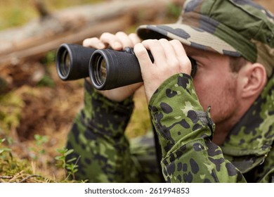 hunting, war, army and people concept - young soldier, ranger or hunter with binocular observing forest - Powered by Shutterstock