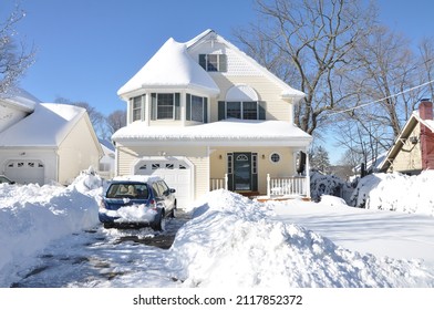 Huntington, New York, USA - February 9, 2013: Parked Car In Front Of Snow Covered Yellow And White Suburban Craftsman Style Home After Northeastern Winter Blizzard Snowstorm Called Nemo.