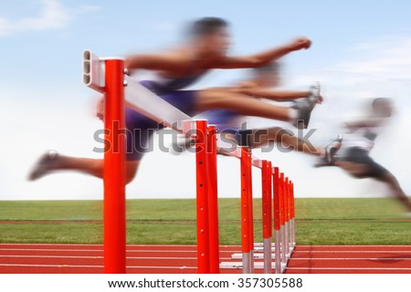 Hurdle race, men jumping over hurdles in a track and field race. Motion blurred image, digitally altered unidentifiable face.
