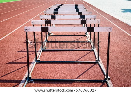 A hurdle race on red running in stadium track