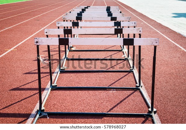 A hurdle race\
on red running in stadium\
track