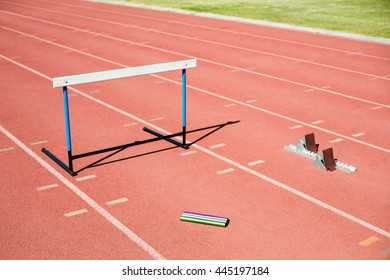 Hurdle, relay baton and a starting block kept on a running track in stadium - Powered by Shutterstock