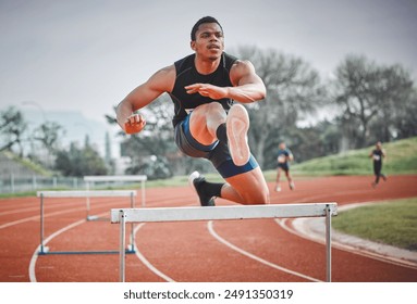 Hurdles, fitness and man running on track at stadium training for race, competition or marathon. Energy, jump and male athlete sprint by equipment for cardio workout or exercise at sports arena. - Powered by Shutterstock