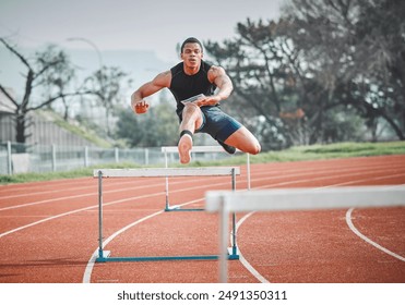 Hurdles, fitness and man sprinting on track at stadium training for race, competition or marathon. Energy, jump and male athlete running by equipment for cardio workout or exercise at sports arena. - Powered by Shutterstock