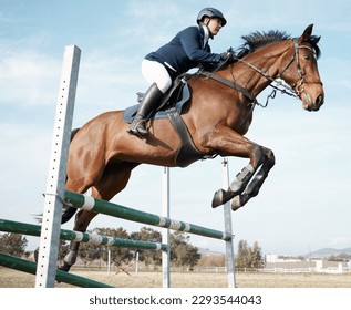 Hurdling obstacles with ease. Full length shot of a young female rider jumping over a hurdle on her horse.