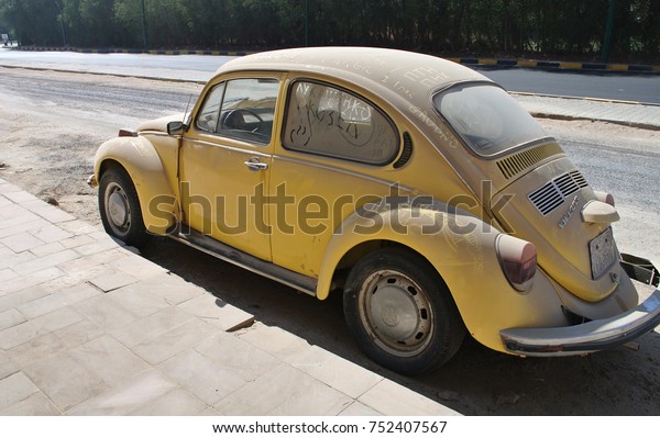 HURGHADA, EGYPT - FEBRUARY 09, 2017: A vintage german\
motor car Volkswagen Beetle in yellow colour parked in a street.\
Dirty car with ukrainian and russian political words written on\
it.