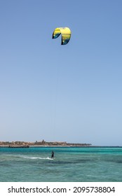 Hurghada, Egypt - June 02, 2021: Kite Surfing Man With Kite In Sky On Board In Sea Riding Waves In Makadi Bay, Which One Of Egypt Beautiful Red Sea Riviera. Kiteboarding Sport.